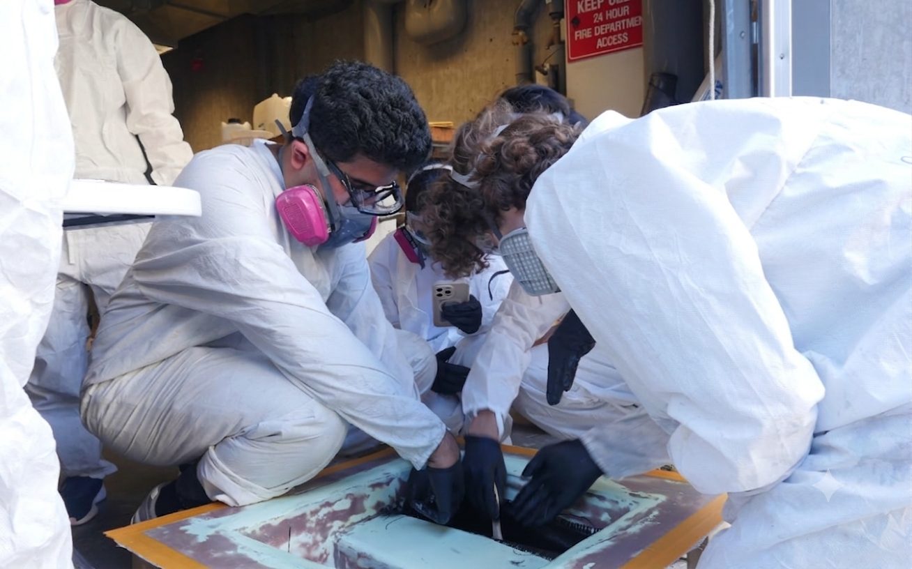 Working with the team in PPE, applying epoxy-wetted carbon fiber to the scaled prototype body.